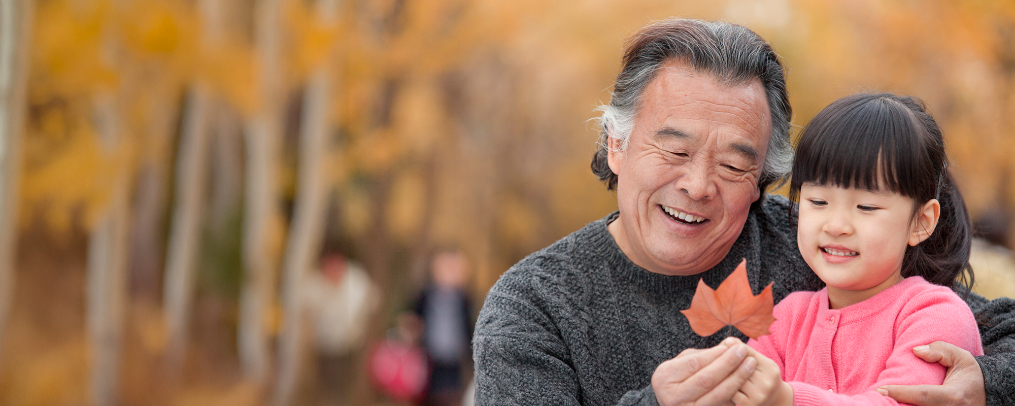 Grandfather and granddaughter look at fall leaf together