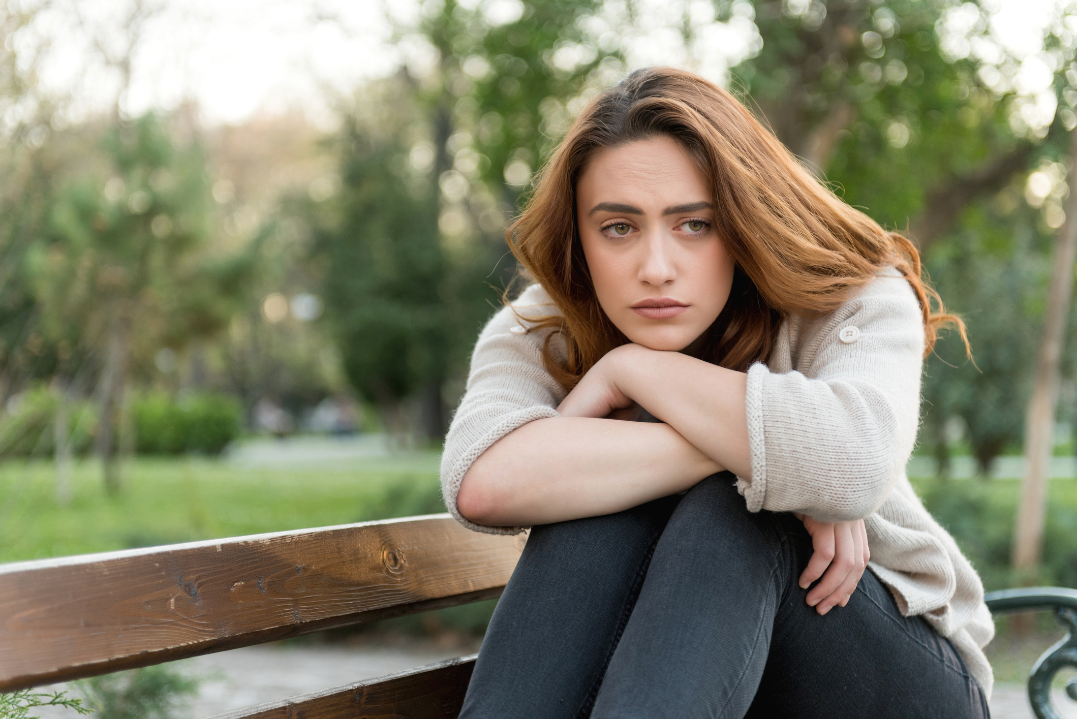 young woman sitting on a park bench feeling anxiety or depression