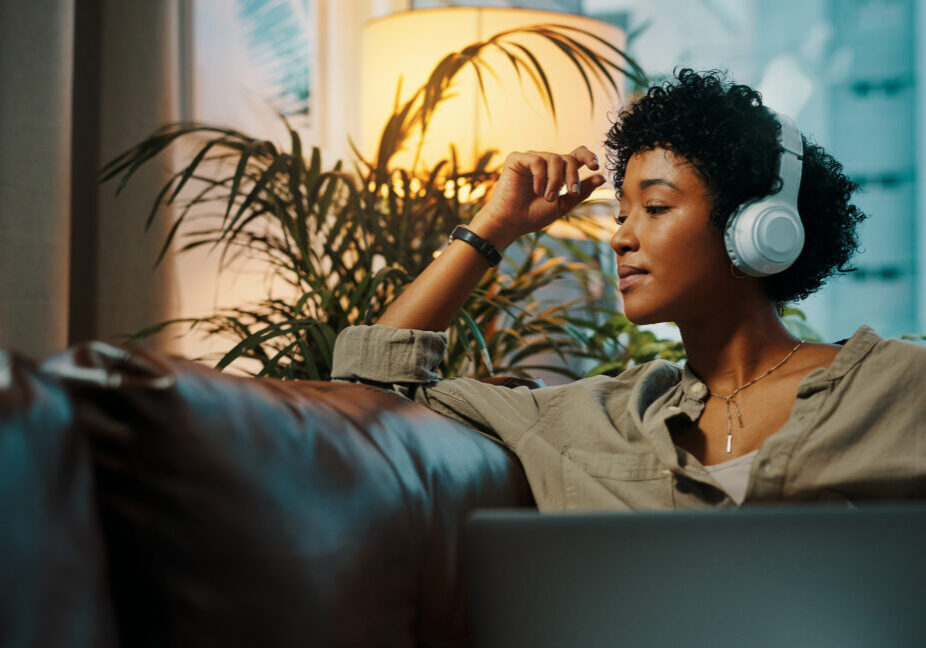 Shot of a young woman wearing headphones while sitting at home with her laptop